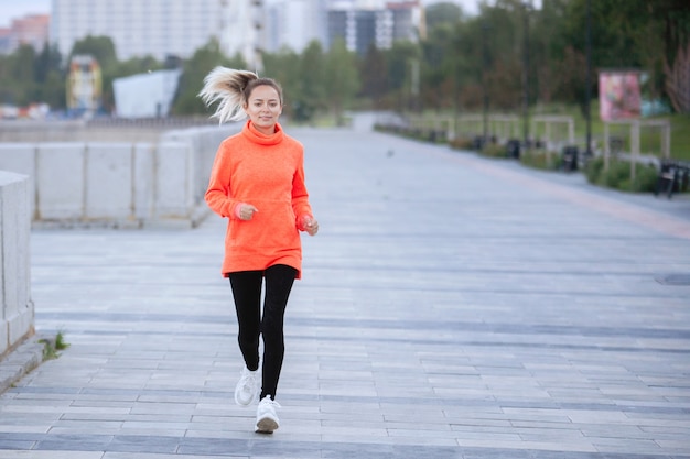 Mujer corre en la acera en una sesión de entrenamiento al aire libre.