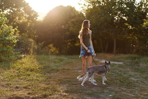 Una mujer corre de espaldas a la cámara con un perro en el bosque durante un paseo nocturno por el bosque al atardecer en otoño Entrenamiento deportivo de estilo de vida con su amado perro