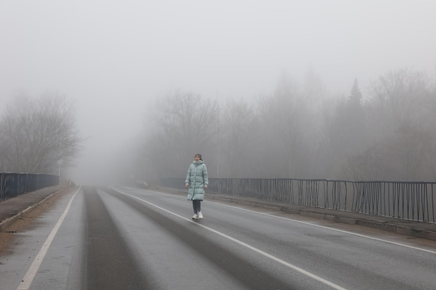 Una mujer corre a lo largo de un camino brumoso en un camino brumoso de un día de otoño