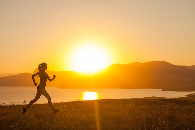 La mujer corre en las montañas en el océano.