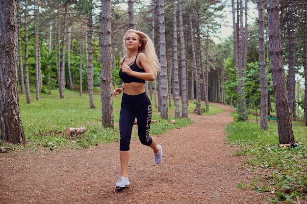 Una mujer corre trotando por el bosque.