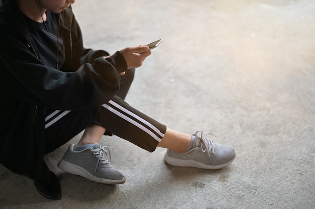 Foto mujer del corredor que usa un teléfono móvil con el teléfono del oído antes de correr en el piso en casa.