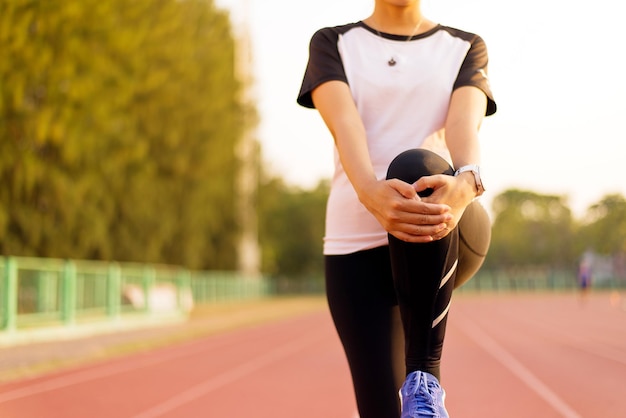 Mujer corredora deportiva estirándose para calentar antes de correr haciendo ejercicios y entrenamiento