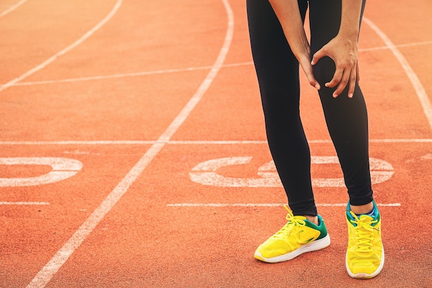 Mujer corredora con lesiones deportivas en la rodilla en el hipódromo manos sosteniendo la rodilla con dolor