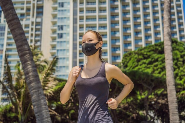 Foto mujer corredora con máscara médica corriendo en la ciudad contra el telón de fondo del coronavirus de la ciudad