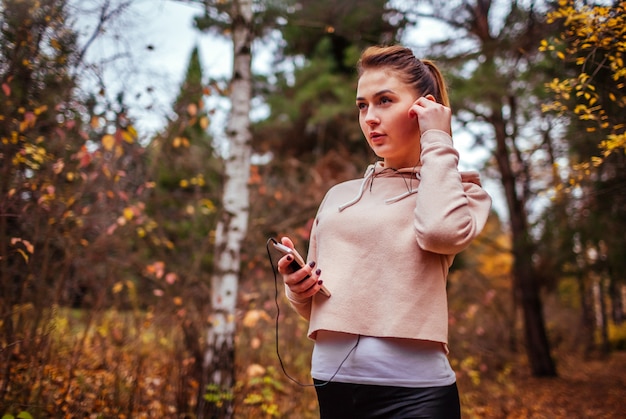 La mujer corredora se pone los audífonos para escuchar la música.