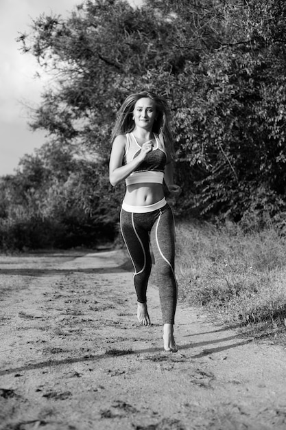 Mujer corredora rubia corre en el parque trotando descalzo, imagen en blanco y negro