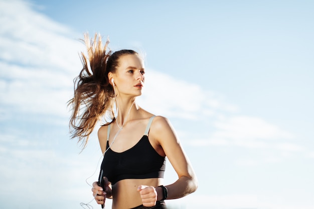 mujer corriendo al aire libre con los auriculares puestos