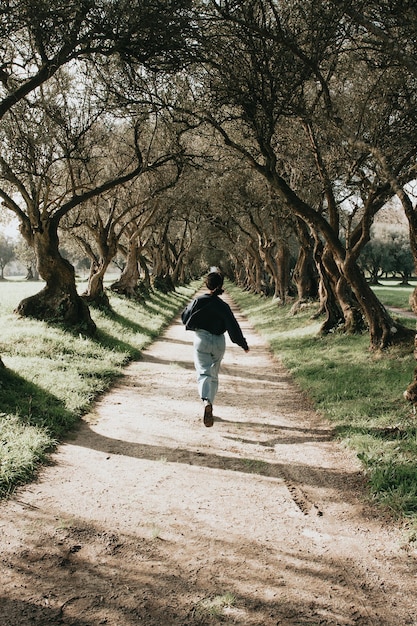 Mujer corriendo entre árboles gigantes en tonos vintage durante un día de primavera