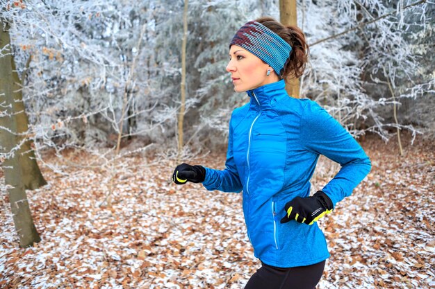 Foto mujer corriendo en el bosque durante el invierno