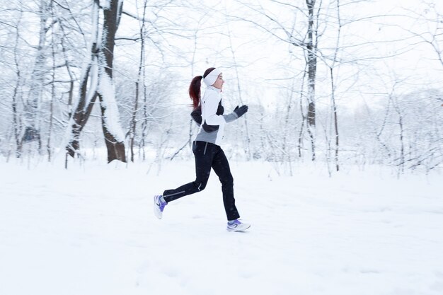 Mujer corriendo en el bosque de invierno