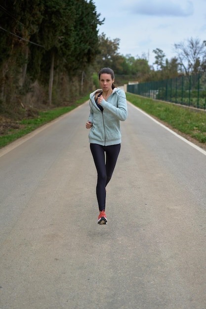 Mujer corriendo por la calle en la vista frontal del bosque