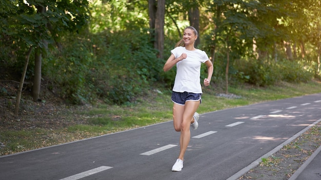 Mujer corriendo carretera de asfalto parque de verano