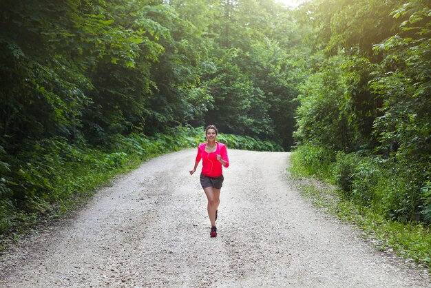 Mujer corriendo por la carretera en medio de los árboles