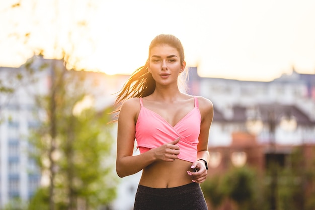 La mujer corriendo en el fondo de la puesta de sol