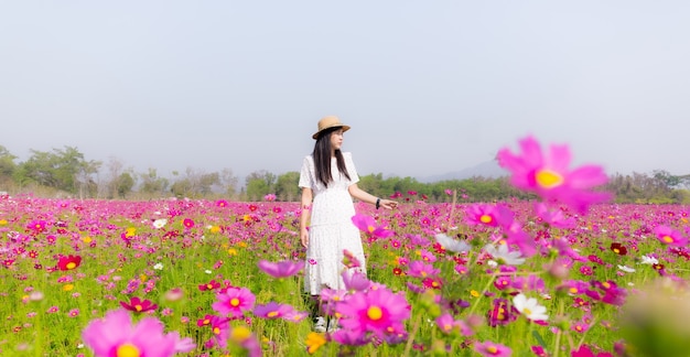 Mujer corriendo en el jardín de flores Cosmos flores para tocarla