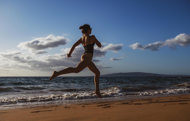 Mujer corriendo a lo largo de las olas del océano junto a la piscina de agua para mantenerse en forma y saludable