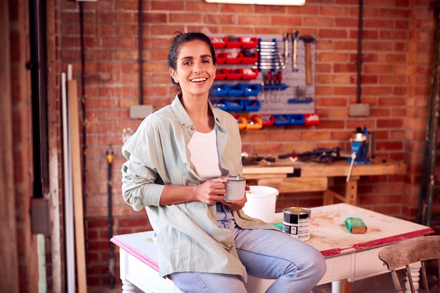 Foto mujer corriendo negocios en taller en casa restaurando y reciclando muebles en coffee break