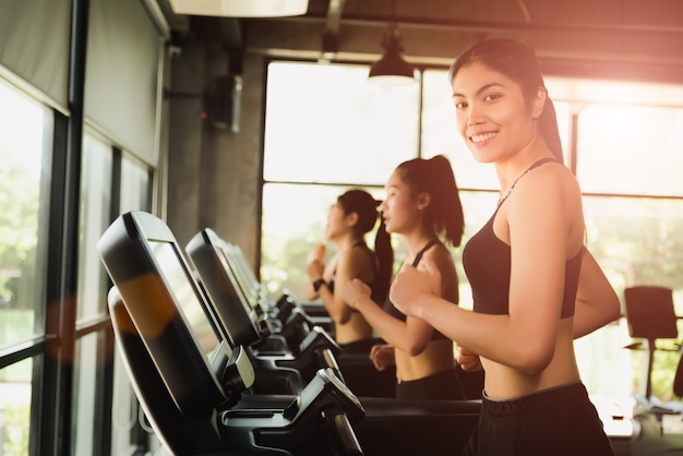 Mujer corriendo o trotando en cintas de correr en el gimnasio deportivo moderno. Concepto de ejercicio y deporte.