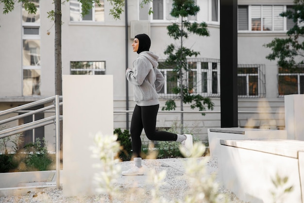 Una mujer corriendo en un parque con una pared blanca detrás de ella.