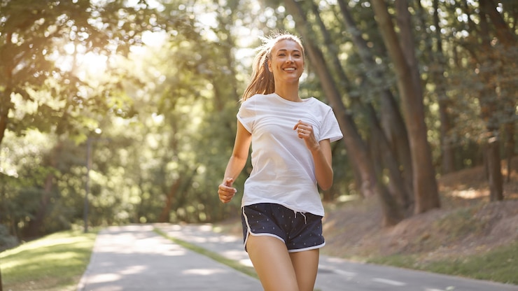 Foto mujer corriendo por el parque de verano de la carretera de asfalto