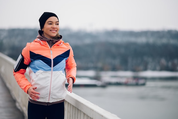 Foto mujer corriendo en el puente en invierno y nieve.