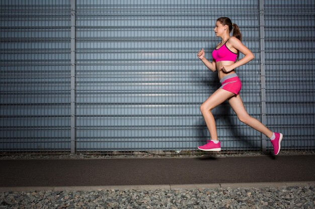 Mujer corriendo. trotar contra el fondo de una pared gris