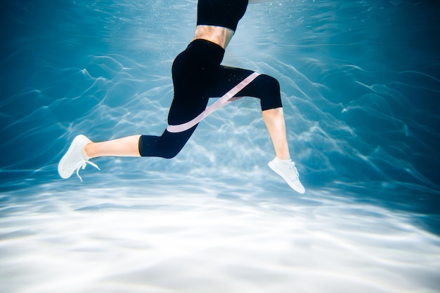 Mujer corriente trotar. Chica bajo el agua, frescura y ligereza, fitness y natación. Deportes y estilo de vida