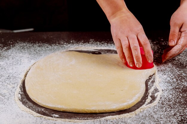 Mujer corta círculos de masa para hacer bollos, dounuts.