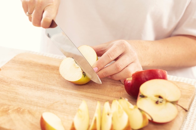 Mujer corta una manzana en rodajas con un cuchillo, primer plano