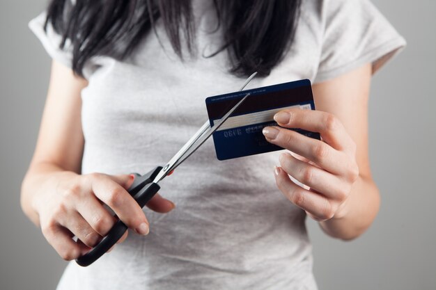 Mujer corta una tarjeta bancaria con unas tijeras