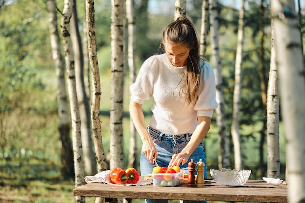 Mujer corta verduras frescas para ensalada durante un picnic al aire libre