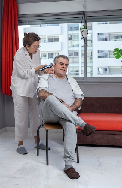 Mujer cortando el cabello de un hombre en casa