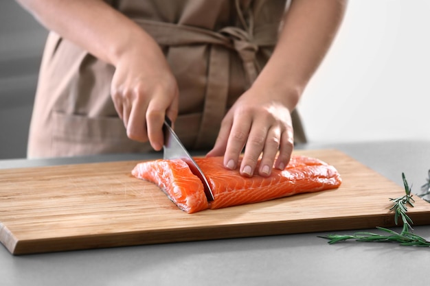 Mujer cortando filete de salmón fresco en la cocina