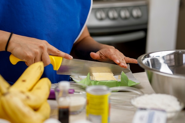 Mujer cortando mantequilla para preparar un panqueque de plátano Concepto para hornear en casa