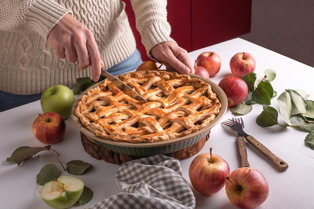 Mujer cortando una manzana al horno con un khife Postre tradicional de Acción de Gracias listo para comer con manzanas rojas y verdes Preparación de tarta de Acción de Gracias panadería de otoño dulces de clima crujiente Receta