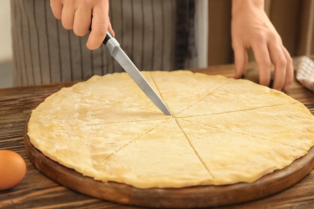 Mujer cortando masa para croissants en la mesa