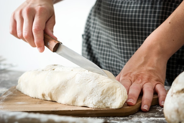 Mujer cortando masa de pan en la mesa de madera