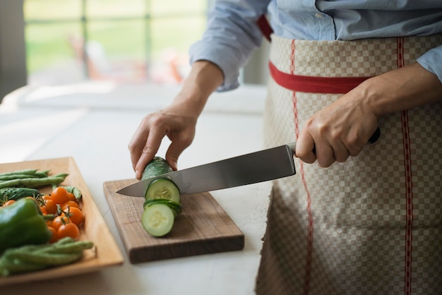 Una mujer cortando pepinos vegetales orgánicos