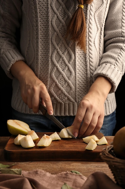 Foto mujer cortando pera en tablero de madera