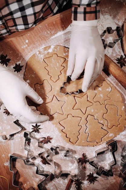 Mujer cortando un poco de masa de pan de jengibre con un cortador de galletas de metal