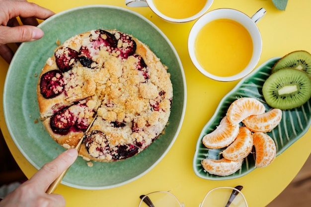 Foto mujer cortando una rebanada de pastel de ciruela crumble