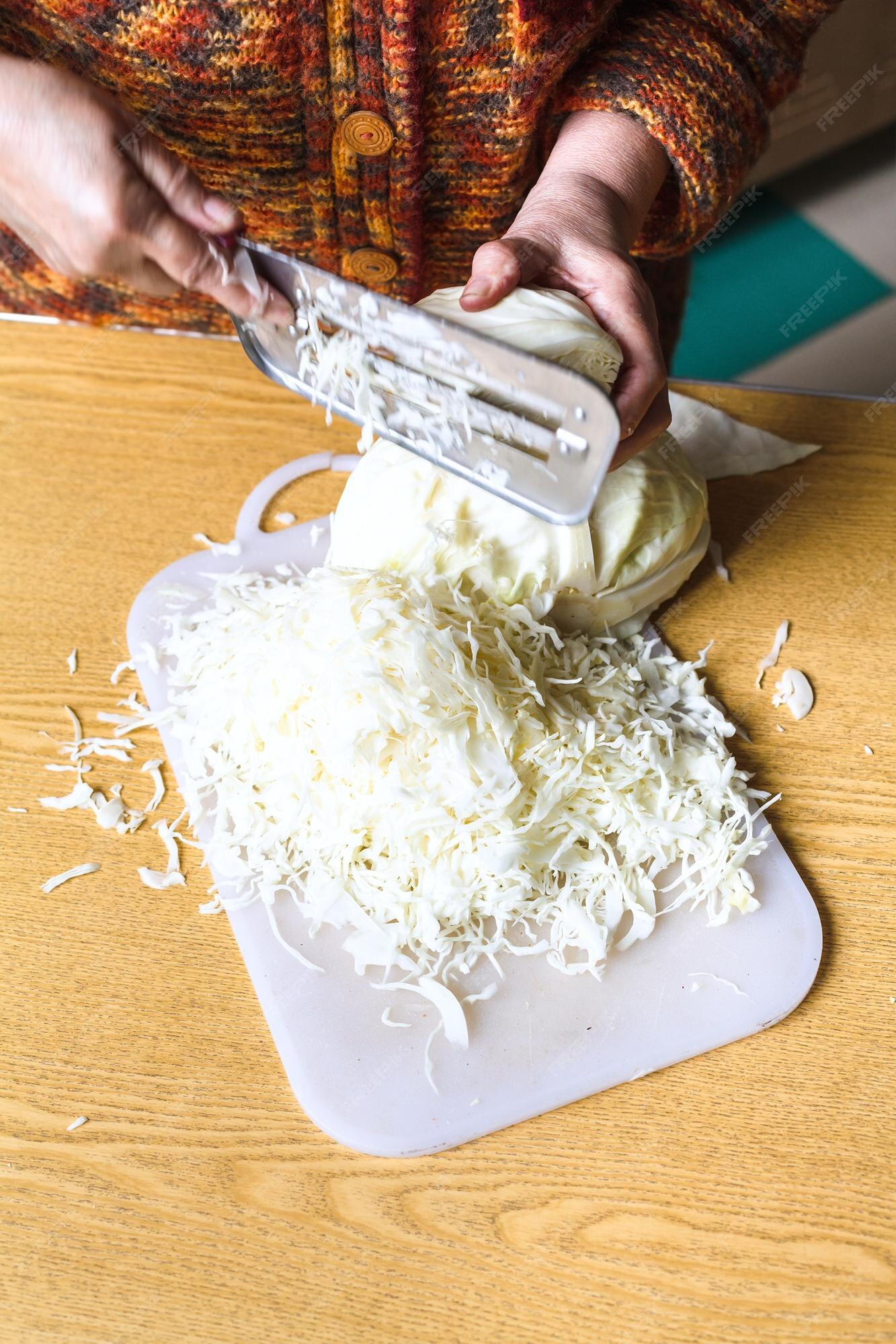 Mujer cortando repollo por cortador de ensalada manual