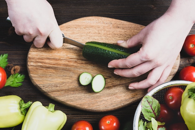 Mujer cortando verduras frescas en una tabla para cortar