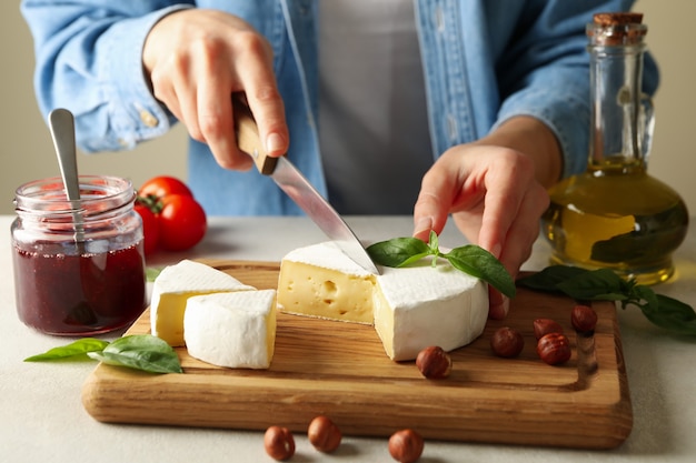 Mujer cortes camembert sobre tabla de cortar, cerrar