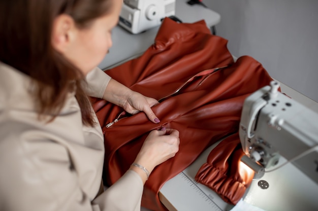 Una mujer cose un artículo de cuero en una máquina de coser.