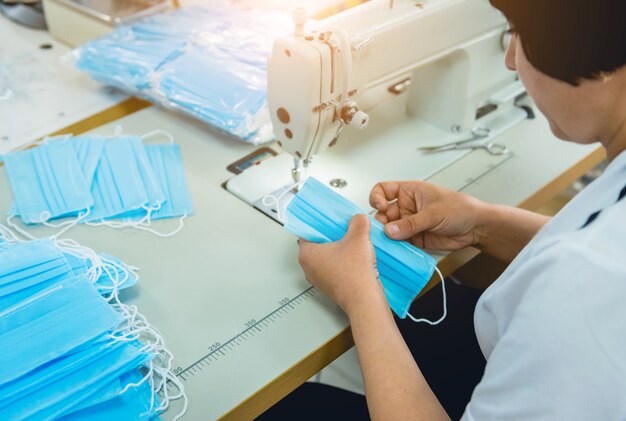 La mujer cose el facial médico en la máquina de coser. Pandemia de coronavirus.