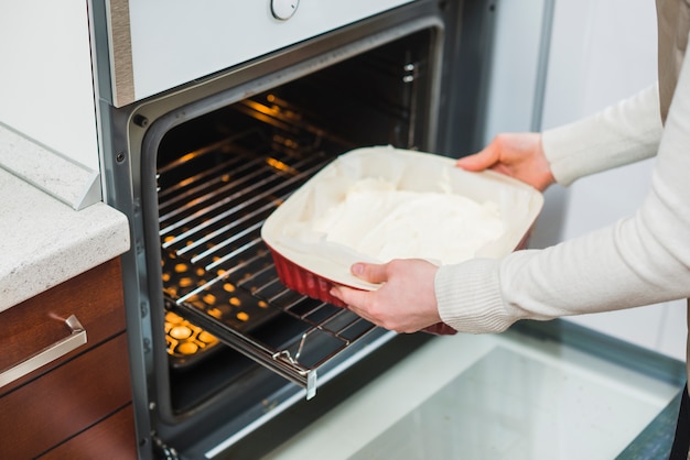 Foto mujer de la cosecha que pone los pasteles en el horno