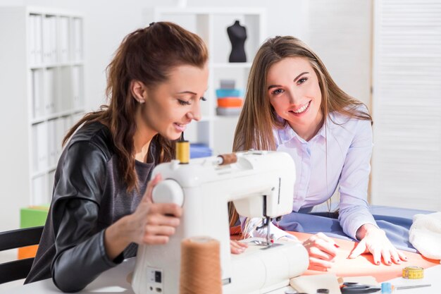 Mujer cosiendo con un colega a su lado