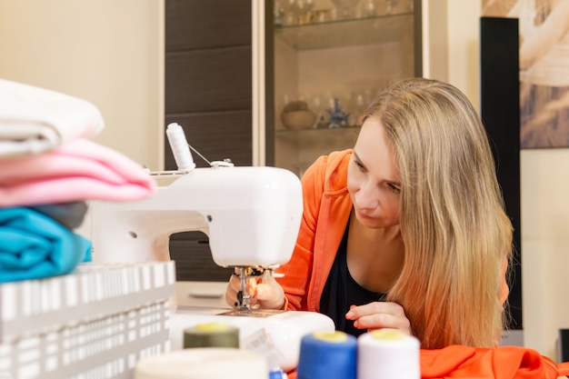 Mujer costurera enhebrar la aguja de una máquina de coser eléctrica